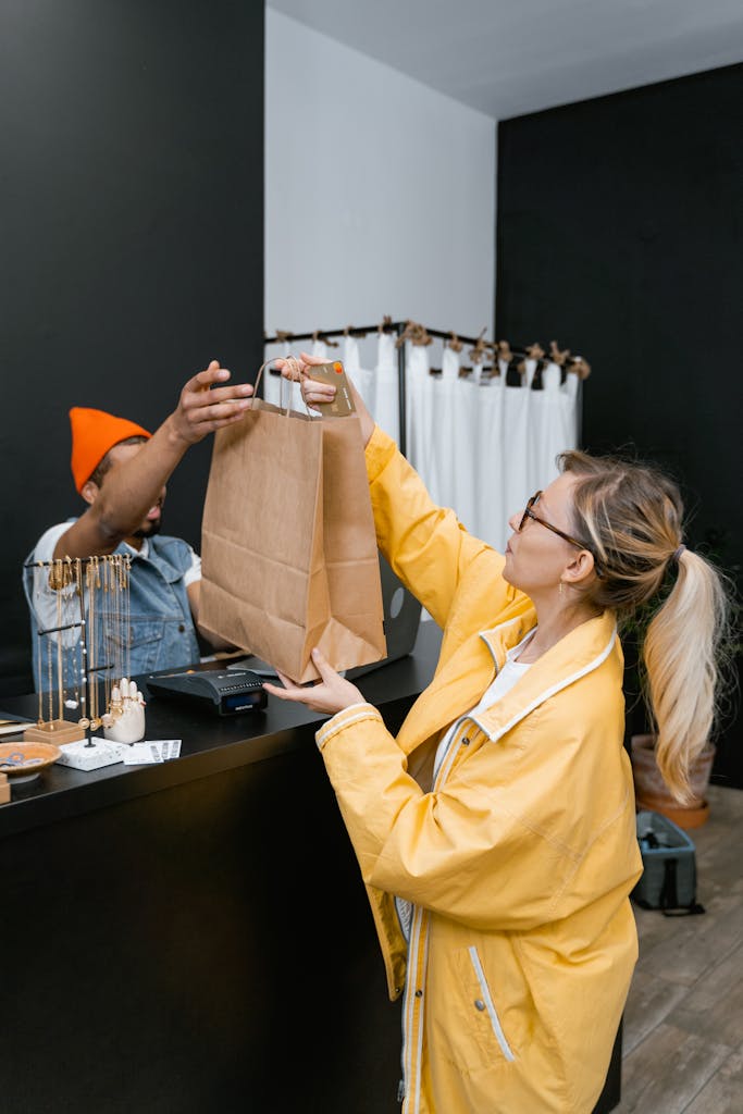 A woman receives a shopping bag from a cashier in a stylish boutique store.