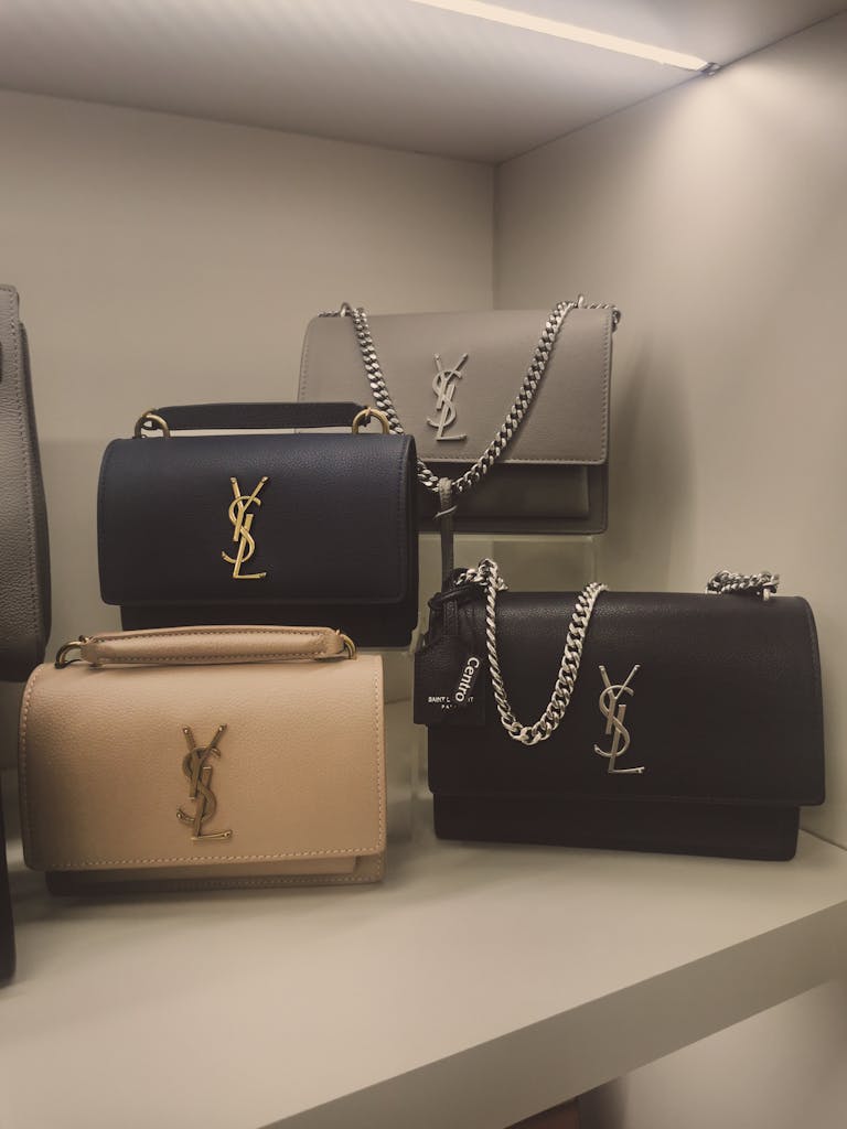 Sleek luxury handbags elegantly displayed on a shelf with chain accents.